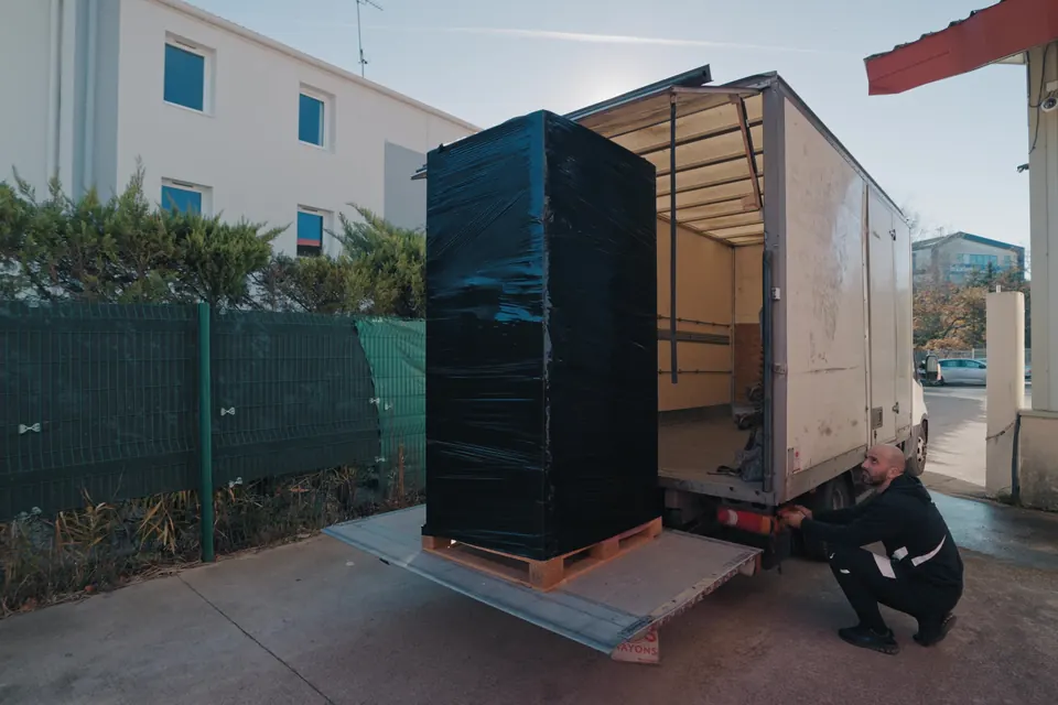 Palette filmée déchargée d'un camion par un manutentionnaire